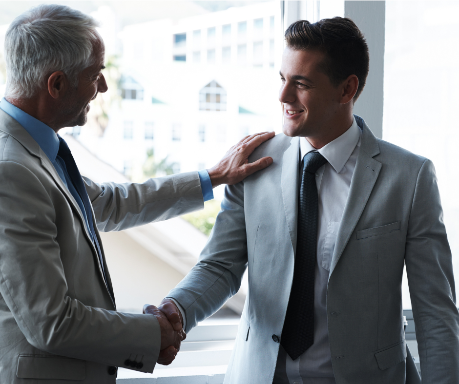 A man in a suit shaking hands with his new manager on his first day of work