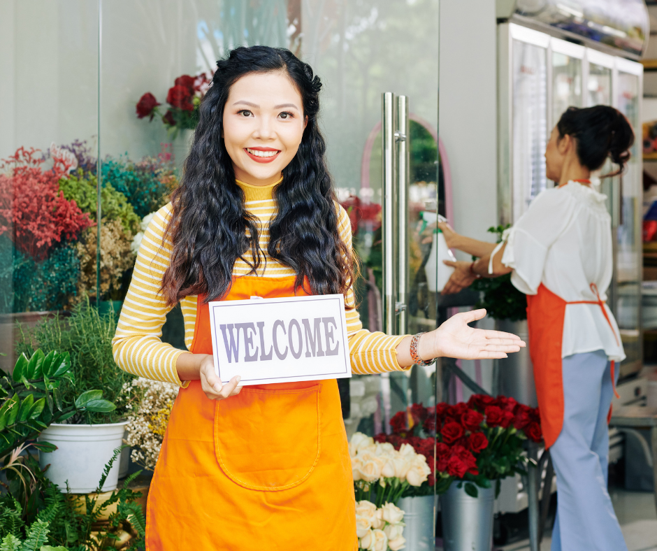 A person smiling and holding a welcome sign